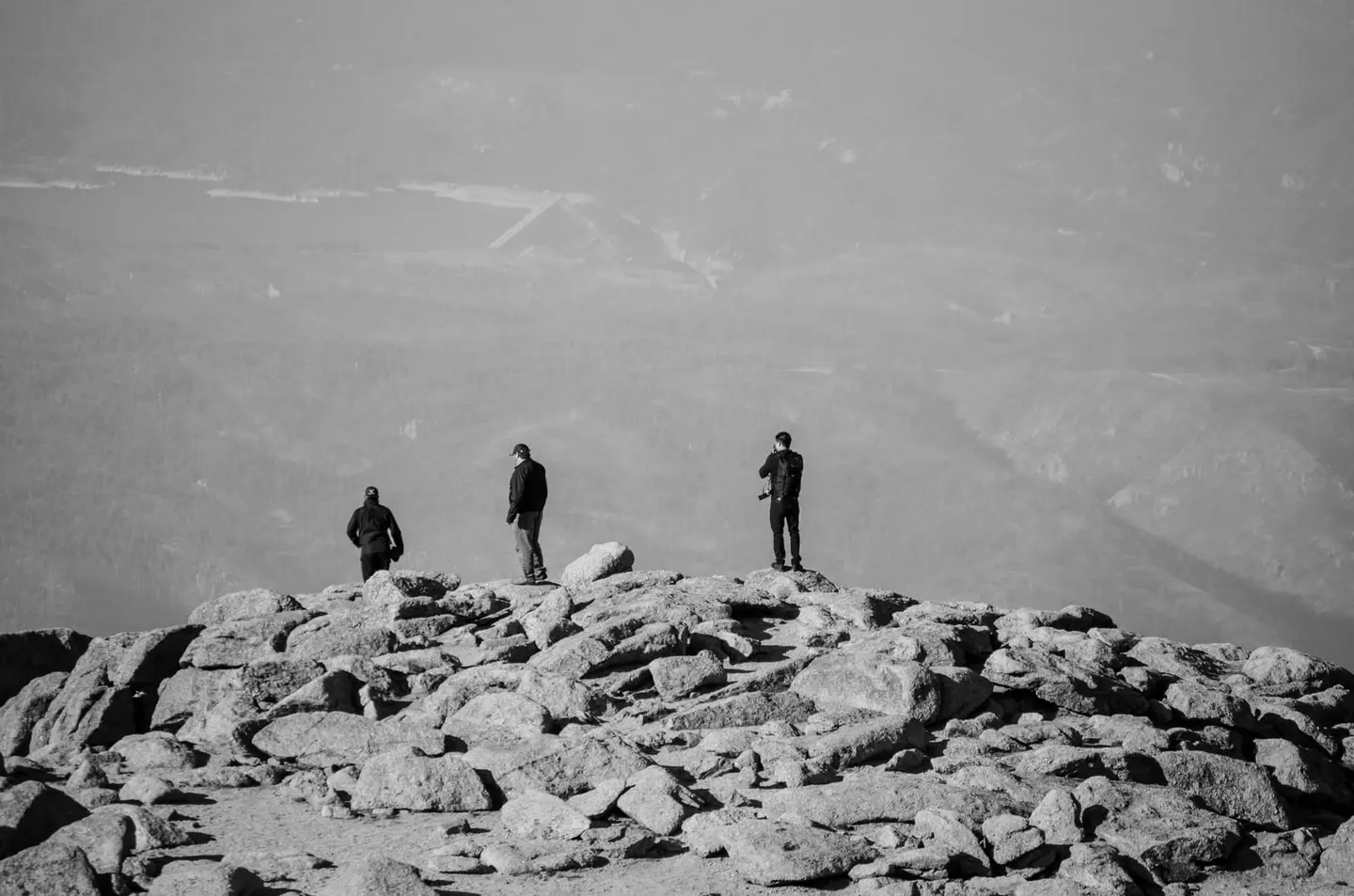Three men look out over Eastern Colorado from the summit of Pikes Peak at an elevation of 4,302 meters.