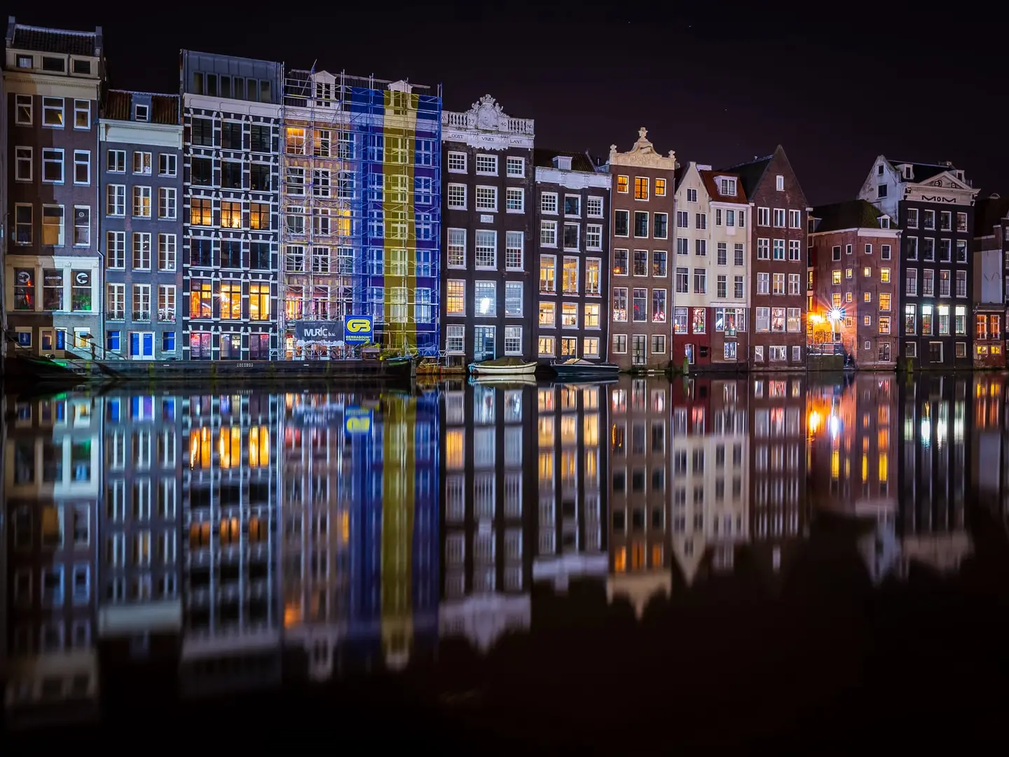 The Damrak waterfront at 00:28 on 14 March 2020, the row of tall historic canal houses perfectly reflected in glassy still water.