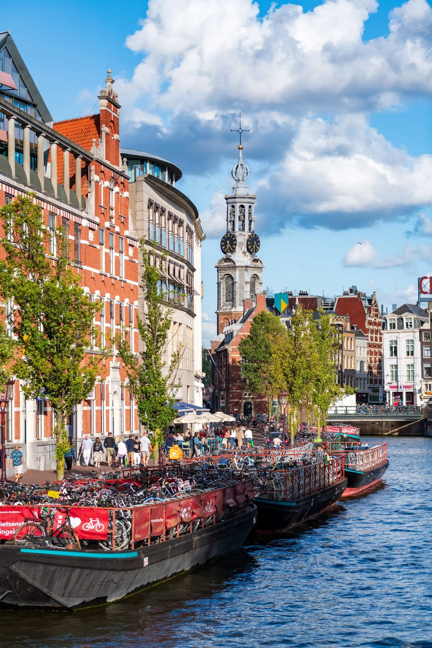 Amsterdam's floating bicycle parking barge moored on the Singel holds hundreds of bicycles in its distinctive red-and-white structure, providing quayside parking for shoppers in the busy city centre.