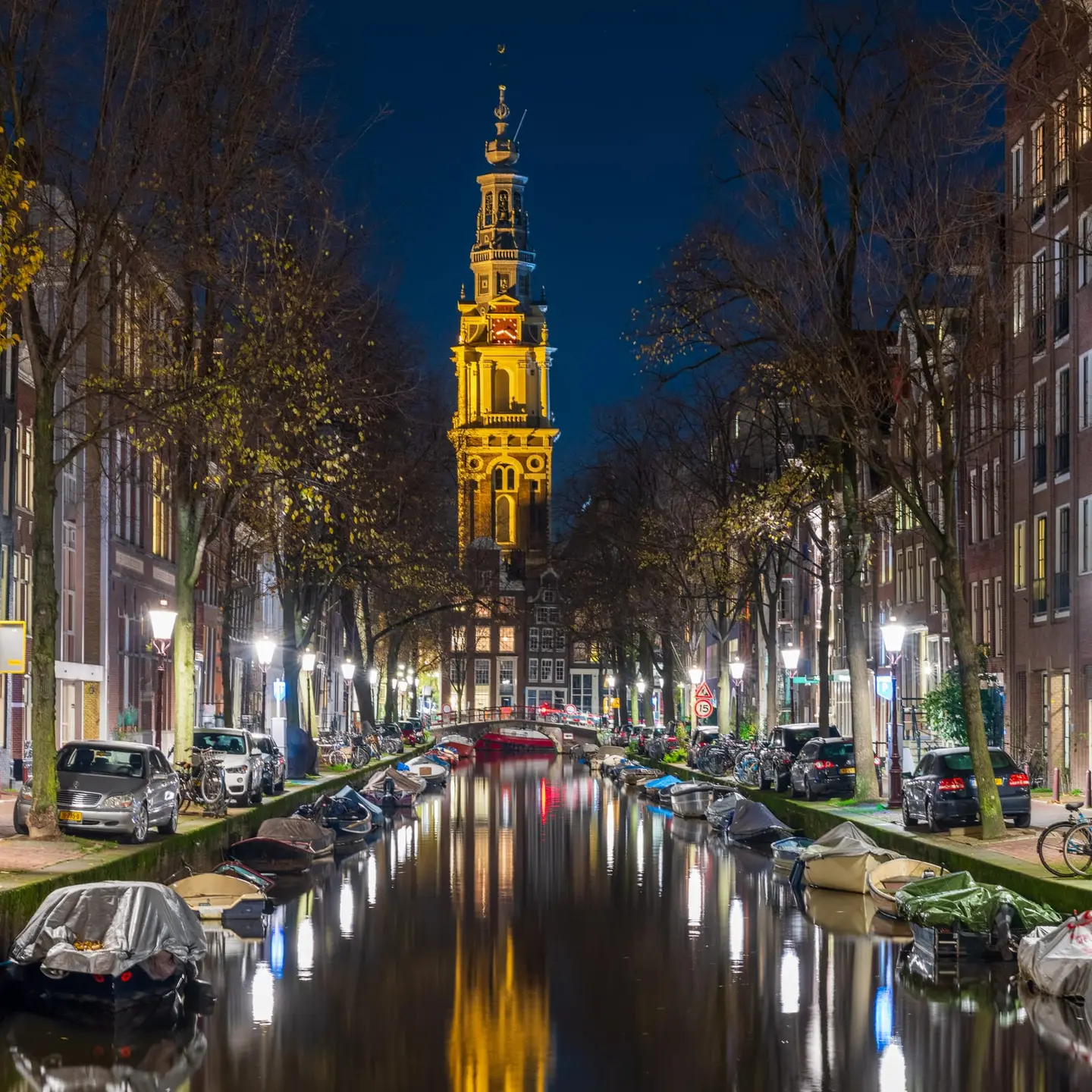 Amsterdam's Zuiderkerk rises as a column of golden light at the end of the Groenburgwal, a narrow canal that leads the eye inescapably toward the illuminated baroque tower.